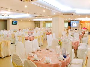 um salão de banquetes com mesas e cadeiras brancas em Bamboo Green Central Hotel em Da Nang