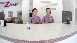 two women in purple shirts standing behind a counter at Hotel Zing Phnom Penh in Phnom Penh