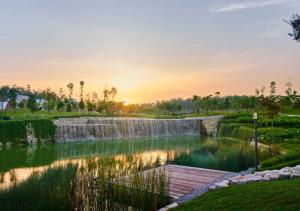 a pond with a waterfall in a park at sunset at AS Homestay Gamuda Gardens Gaia Residence 2R1B Rawang Skyline Luge in Rawang