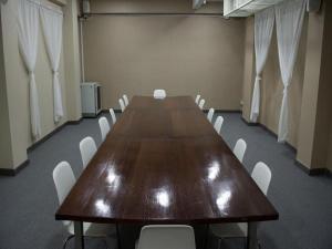 a conference room with a long table and white chairs at Veethara boutique hotel in Udon Thani
