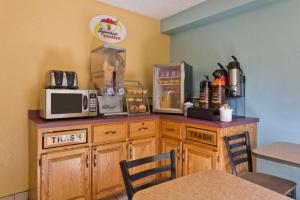 a kitchen with a counter with a microwave and a table at Super 8 By Wyndham Lexington Park/California Area in California