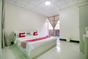 a white bedroom with a large bed with red pillows at OYO 75390 Sunee Place Hotel in Rayong