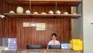 kobieta siedząca przy ladzie z laptopem w obiekcie H Life Hotel (Shenzhen Sea World Branch) w mieście Shenzhen