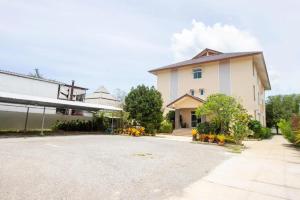 un grand bâtiment blanc avec des fleurs dans une allée dans l'établissement OYO 904 Mai Thai Place, à Hua Hin