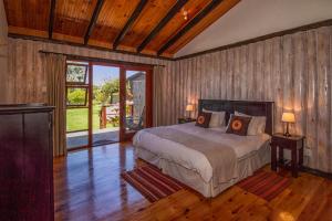 Piesang Valley Lodge في بليتنبيرغ باي: غرفة نوم بسرير في غرفة ذات أرضيات خشبية