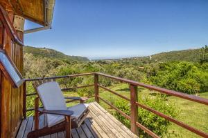 a rocking chair sitting on a wooden deck with a view at Piesang Valley Lodge in Plettenberg Bay