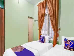 Hotel O Nayla Homestay Syariah Near Koro Koro Panam, Karaoke, Pool, & Cafe في Sultan Syarif Kasim II International Airport: سريرين في غرفة بها نافذة