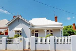 a white picket fence in front of a white house at The Warra House in Dubbo