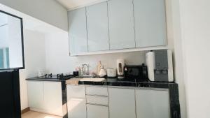 a kitchen with white cabinets and a black counter top at Inara Homestay in Kuala Lumpur