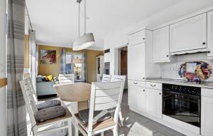 a kitchen with white cabinets and a table and chairs at Nice Home In Glowe With Wifi in Glowe