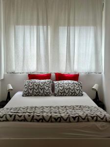 ein Schlafzimmer mit einem Bett mit roten Kissen und einem Fenster in der Unterkunft Apartman Moonlite in Čakovec