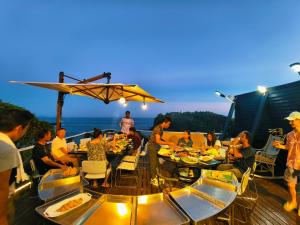 um grupo de pessoas sentadas em mesas num convés em 湯と風の宿 恵比寿 em Shimoda