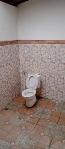 a bathroom with a toilet in a tiled wall at D'karang Eco Lodge in Undisan