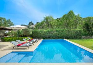 a pool with lounge chairs and an umbrella at Can Menonge by Vintage Travel in Pollença