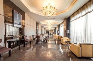 a hotel lobby with chairs and tables and a chandelier at Cinese Hotel Dongguan in Dongguan