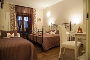 a bedroom with two beds and a chair and a table at La Locanda di Mariella dal 1950 in Poggio Picenze