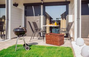 a grill on a patio with chairs and a table at 2 Bedroom Cozy Home In Sarbinowo in Sarbinowo +9 photos