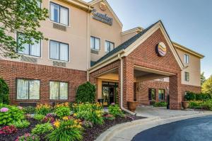 a hotel exterior with flowers in front of a building at Comfort Inn & Suites University South in Ann Arbor