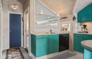 3 Bedroom Cozy Home In Otterup في Otterup: مطبخ مع خزائن زرقاء ومغسلة