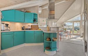 3 Bedroom Cozy Home In Otterup في Otterup: مطبخ مع دواليب زرقاء وطاولة مع كراسي