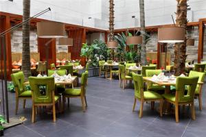 ein Restaurant mit Tischen und grünen Stühlen in einem Restaurant in der Unterkunft Shenyang Haiyun Jinjiang International Hotel in Shenyang