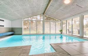 an indoor swimming pool with a large window at Gorgeous Home In Knebel With Sauna in Skødshoved Strand +34 photos