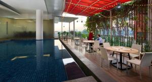 a swimming pool with tables and chairs next to a restaurant at Cipta Hotel Pancoran in Jakarta