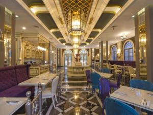 Un restaurante con mesas y sillas y una lámpara de araña. en d'primahotel Bandung, en Bandung