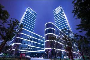 two tall buildings are lit up at night at LONGYAN JINGHUA FLIPORT HOTEL in Longyan