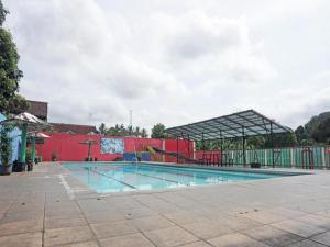 a large swimming pool with a red building and a building at Hotel O Amazon Homestay Syariah 2 in Sukabumi