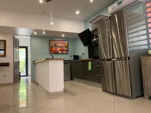 a kitchen with stainless steel appliances and a tv at Villa Zélie, avec piscine et proche du lagon in La Saline Les hauts 