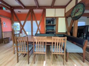 a wooden dining room table with chairs and a clock at Misato Guest House in Suita