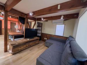 a living room with a blue couch and a tv at Misato Guest House in Suita