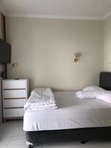a bedroom with a bed with white sheets and a dresser at Bernice Homestay Syariah 1 Wonosobo in Wonosobo