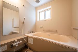 a bathroom with a tub and a window and a sink at Shibuonsen House in Yamanouchi +4 photos