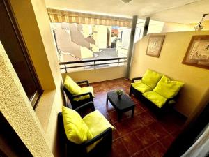 a room with yellow pillows and chairs and a balcony at Sol & Mar in El Médano