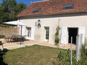 a white house with a table and an umbrella at Domaine de Praline - Le potager de Justin in Villerbon
