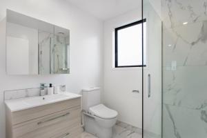 a white bathroom with a toilet and a glass shower at Prime Location Cosy Warm Free Off Street Park in Addington