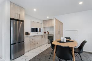 a kitchen with a table and chairs and a refrigerator at Prime Location Cosy Warm Free Off Street Park in Addington +10 photos