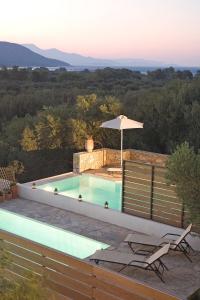 a swimming pool with two chairs and an umbrella at Istron Maisonettes with private pool in Istro