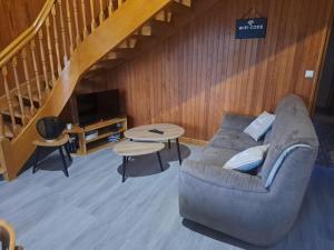 a living room with a couch and a staircase at Maison La Roche du Miroir in Plaimbois-du Miroir