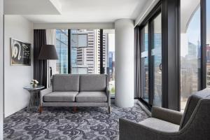 a living room with a couch and a chair and windows at Sheraton Melbourne Hotel in Melbourne +98 photos