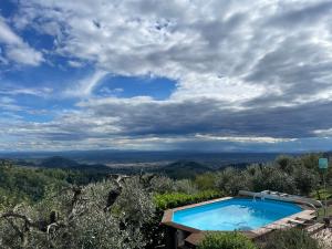 a swimming pool on top of a hill with a cloudy sky at Podere il Poggio in Avaglio