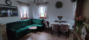 Una sala de estar con un sofá verde y una mesa. en Słoneczna Chałupka, en Zawoja