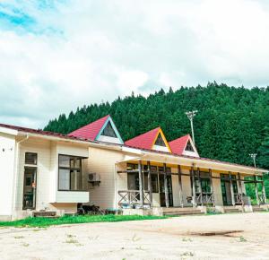 a building with red roofs in front of a mountain at まるもりビレッジ in Wada