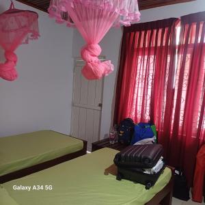 a bedroom with two beds and pink curtains at Muthupalasa in Anuradhapura