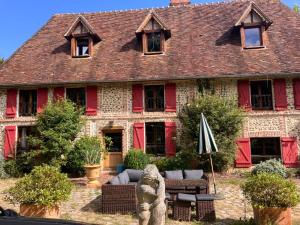 a large house with red doors and a bear statue in front of it at La maison normande 5 chambres in Anciens