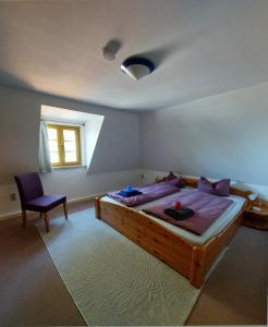 a bedroom with a large wooden bed and a chair at Lotterhof Ferienhaus Gartenhaus in Augustusburg