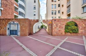 a brick wall with an archway in a parking lot at Appartement familial proche métro in Créteil