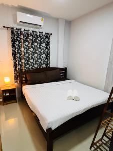 ein Schlafzimmer mit einem Bett mit zwei weißen Schuhen darauf in der Unterkunft บ้าน2ห้องนอน1ห้องน้ำเงียบสงบเดิน10นาทีถึงชายหาด in Ban Khlong Haeng